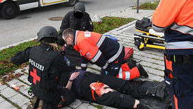 Ein Malteser Sanitäter beugt sich über einen Verletztendarsteller. 